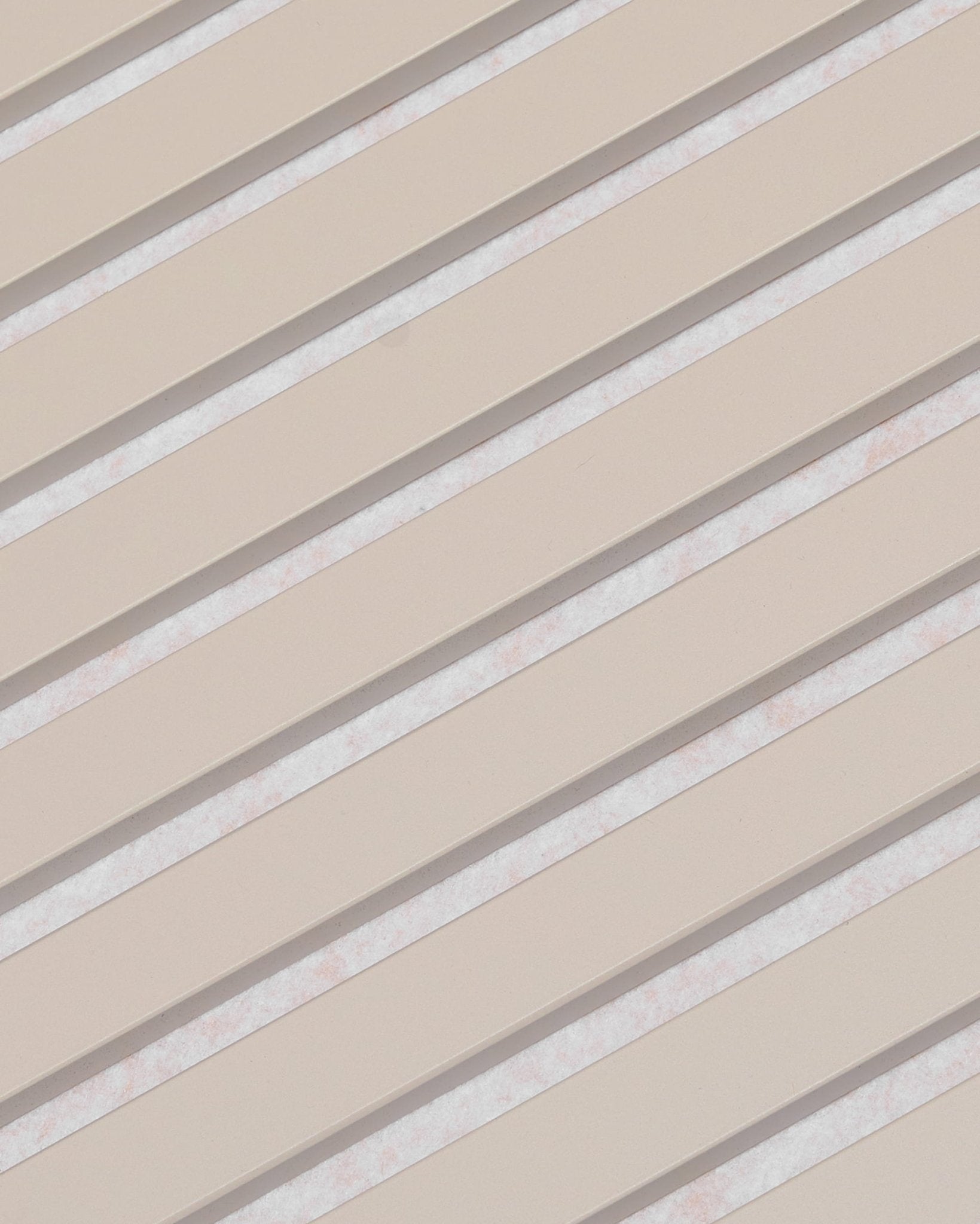 Ukośne beżowe listwy z białymi przerwami tworzą wzór w paski na panelu akustycznym WoodUpp Akupanel, wykończonym filcem w kolorze Soft Linen Light Beige, o wymiarach 240 x 60 cm.